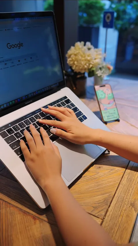 Ноутбук и смартфон на деревянном столике у окна кафе