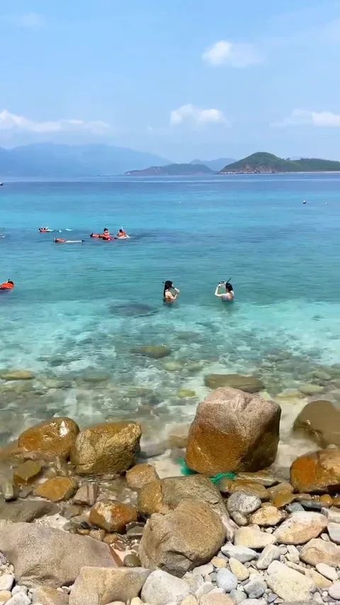 Галечный берег с валунами и снорклеры в прозрачной воде Хон Мун
